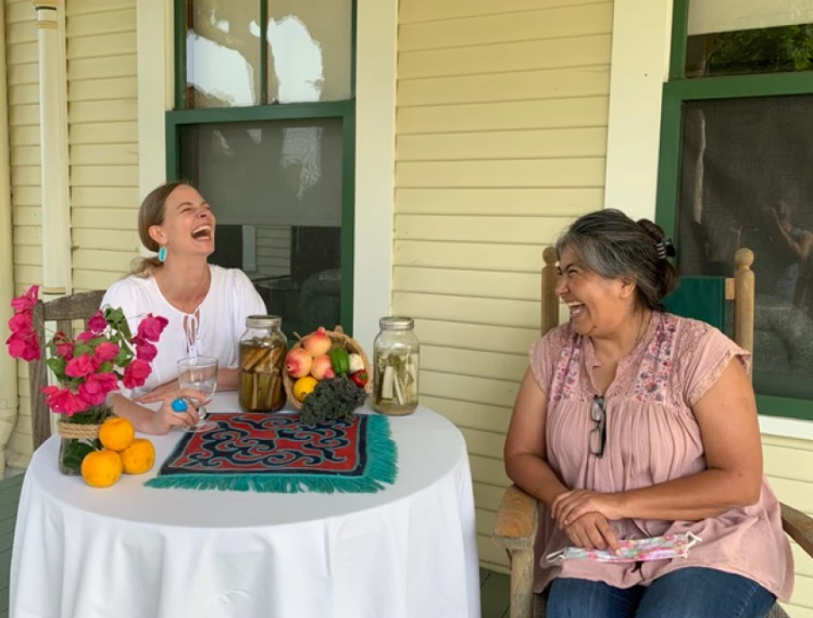 photo of 2 women sitting at table laughing